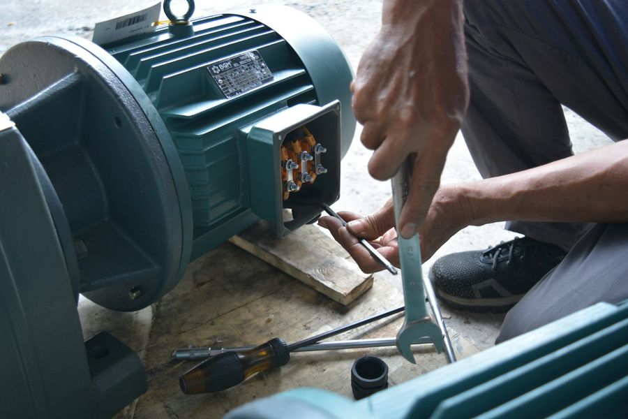 Mãos de um técnico ligando o terminal de um equipamento elétrico
